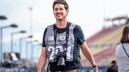 Person smiling with a camera around their neck.