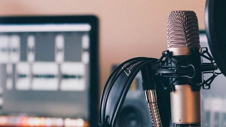 A microphone in front of a computer screen.