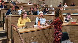 Whitney Phillips speaks to two students in a large classroom