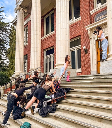 students pose for a photographer on the steps of Johnson Hall at the University of Oregon campus