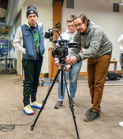 students gather around a video camera