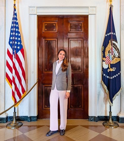 Priya Sage poses in front of a door at the White House