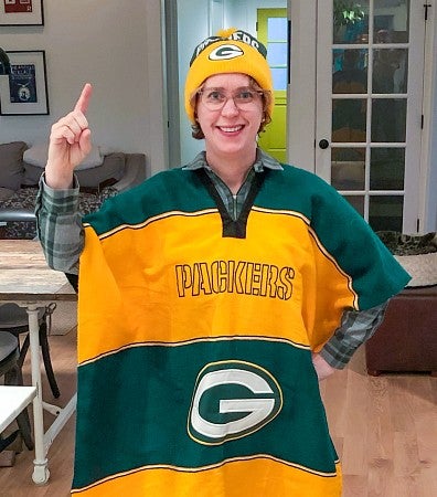 Christine Wise poses in a green and gold striped Green Bay Packers poncho