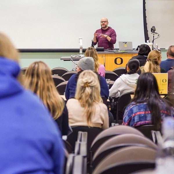 Dean Mundy speaks at the front of a large classroom