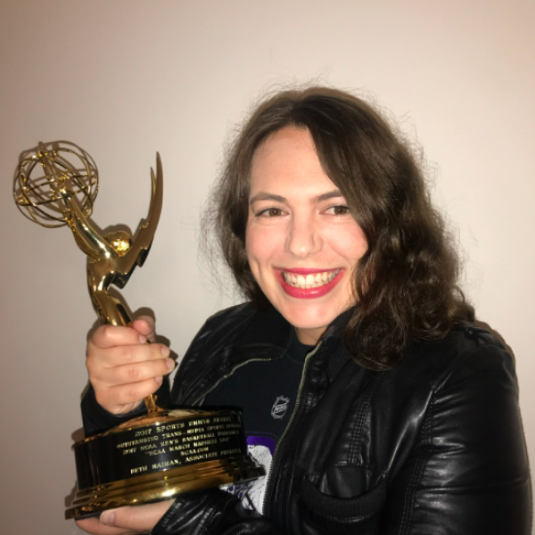 Beth Maiman smiles at the camera while holding the Sports Emmy Award she received in 2017.