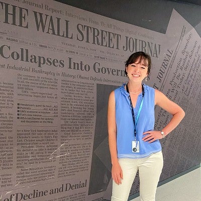 Sierra McClain poses in front of a wall with images of the Wall Street Journal