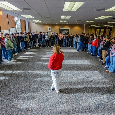 a college student stands surrounded by high school students as she prepares to engage with them about their trust in media