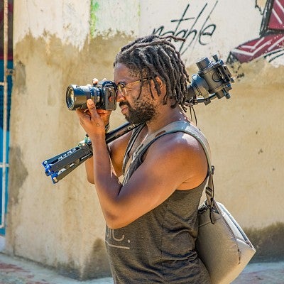 John Adair shooting a photo while holding a tripod over his shoulder