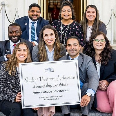 A group of student veterans pose with a sign that says "Student Veterans of America Leadership Institute"
