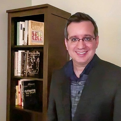 Daniel Zweifach stands next to a bookcase