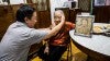 Setyawan’s uncle poses with her great aunt for a photo with a drawing of her younger self in their family home in central Jakarta.  Photo by Kezia Setyawan.